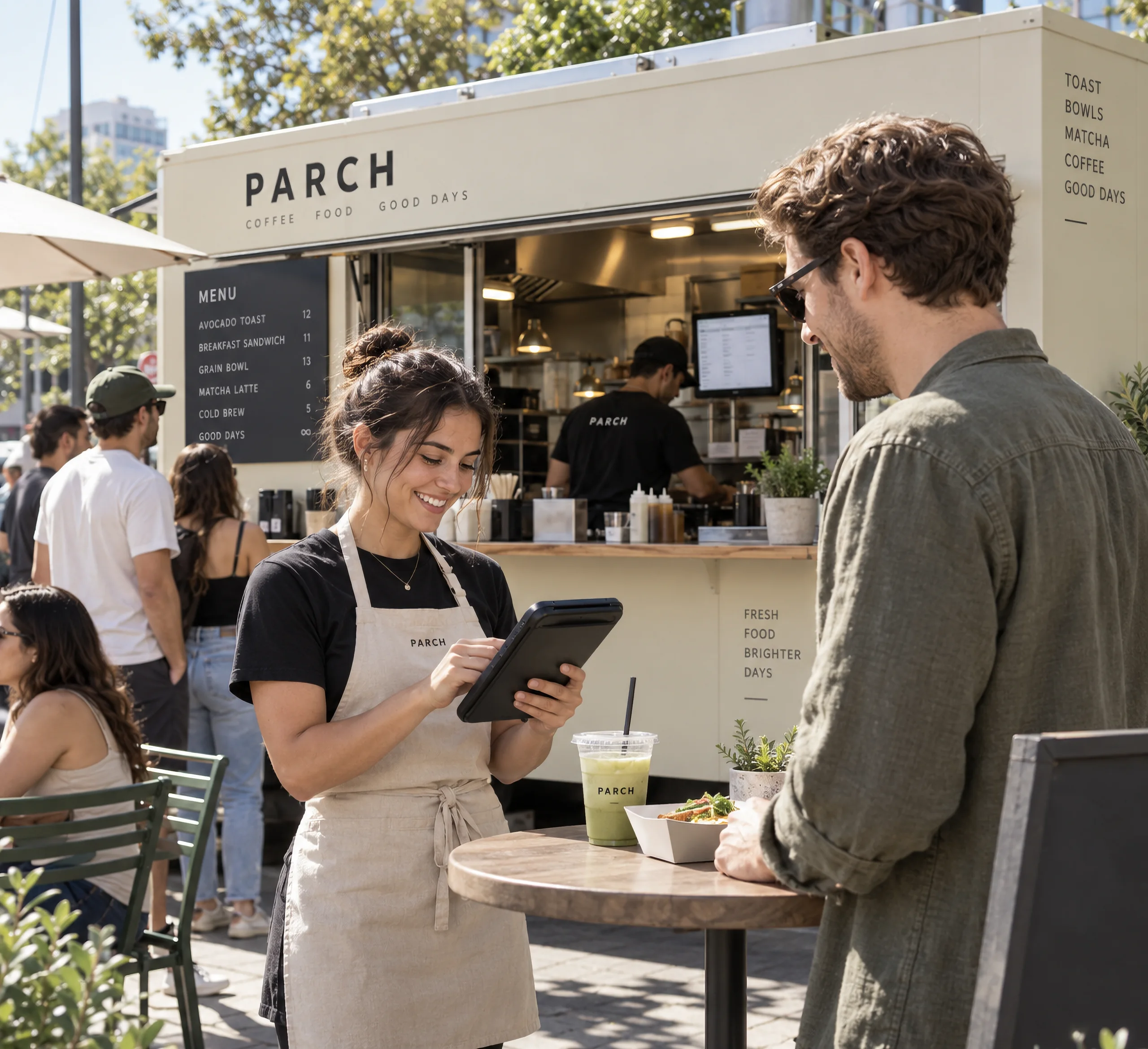 Barista taking an order on a tablet at an outdoor coffee bar