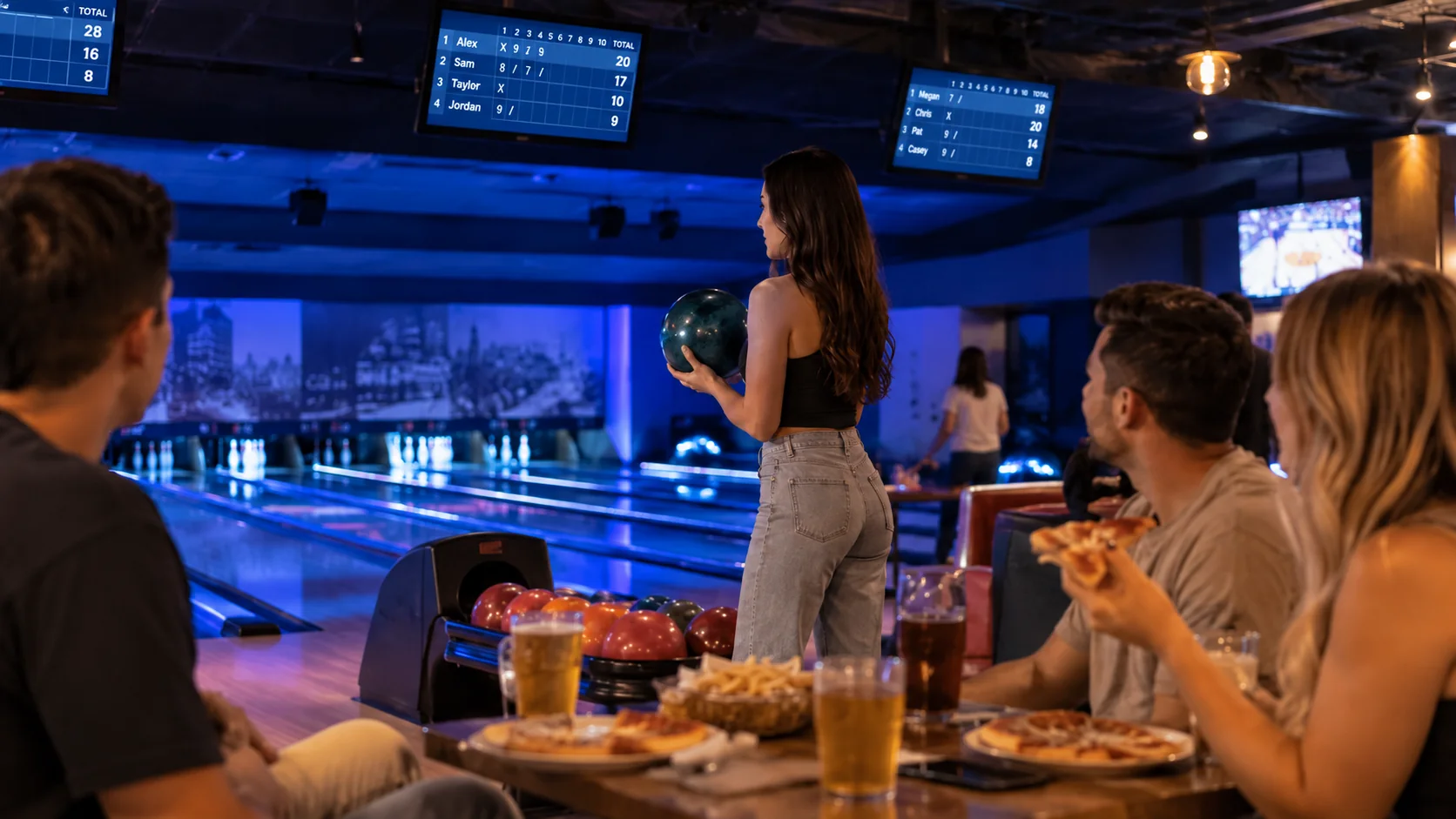 Friends eating at a table beside the lanes in a bowling alley